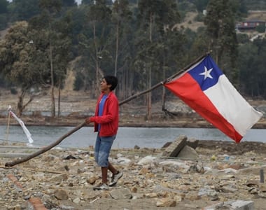 A man holds a Chile's flag on the shores of Maule river in Constitucion, south of Santiago, March 11, 2010.. REUTERS/David Mercado