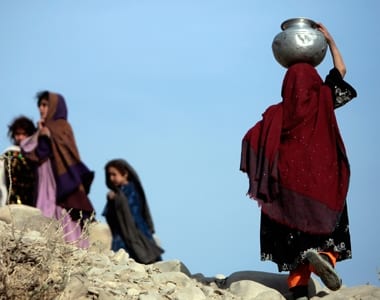 An Afghan girl carries a water pot while other girls watch U.S. Army soldiers from Task Force Bravo 2/151 infantry patrol at Alo Khil village in Khowst province, Afghanistan.. REUTERS/Zohra Bensemra
