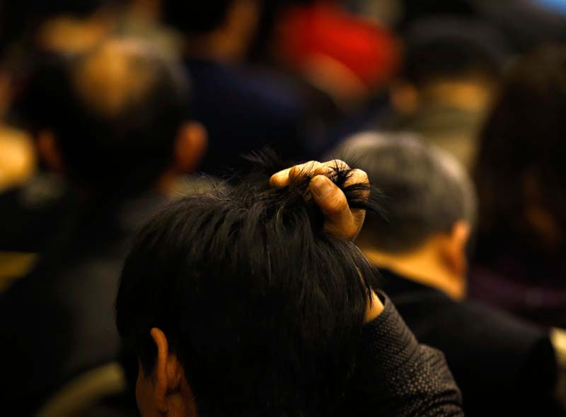 A family member of a passenger onboard the missing Malaysia Airlines Flight MH370 grabs his hair during a briefing by the Malaysian government at a hotel in Beijing March 21, 2014. An international search force resumed the hunt for the missing Malaysia Airlines Flight MH370 in the remote southern Indian Ocean on Friday as authorities pored over satellite data to try and confirm a potential debris field.    REUTERS/Kim Kyung-Hoon 