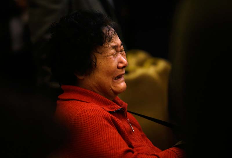 A family member of a passenger onboard Malaysia Airlines Flight MH370 cries as other relatives shout slogans to protest against the lack of new information after a routine briefing given by Malaysia's government and military representatives at Lido Hotel in Beijing March 22, 2014. Two weeks after a Malaysia Airlines airliner went missing with 239 people on board, officials are bracing for the "long haul" as searches by more than two dozen countries turn up little but frustration and fresh questions.REUTERS/Jason Lee 