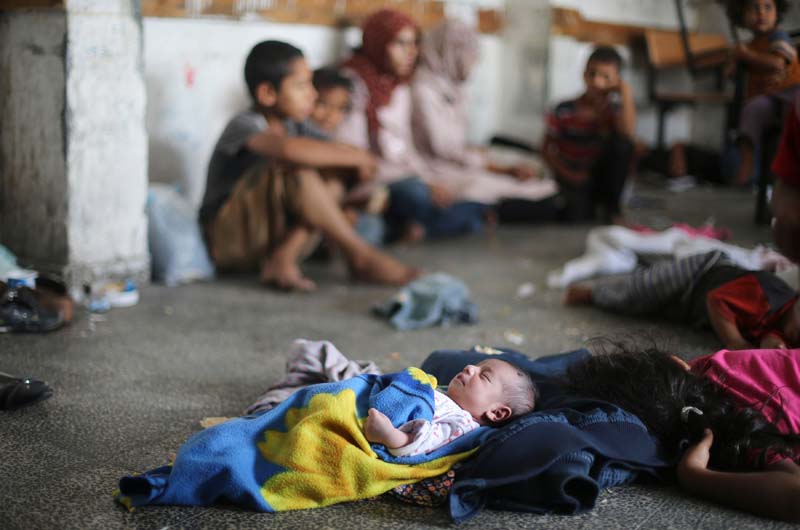 Palestinian children, who fled their families' houses following an Israeli ground offensive, sleep as they stay inside a classroom at a United Nations-run school in Rafah in the southern Gaza Strip July 19, 2014. REUTERS/Ibraheem Abu Mustafa