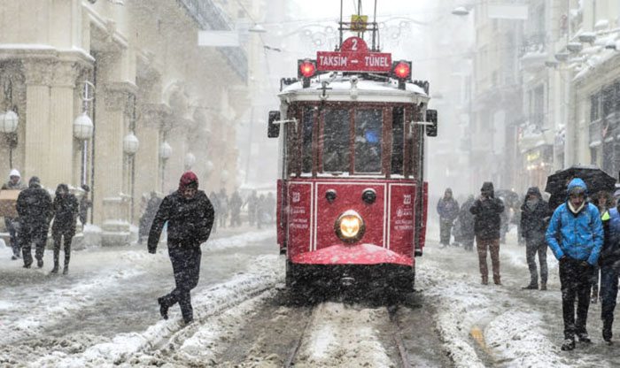 People walk next to a tramway on Istanbul's main shopping street, Istiklal Avenue, during the weekend's heavy snowfalls.