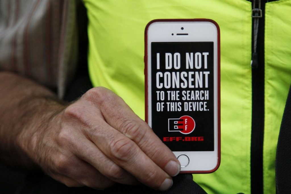 A man holds up his iPhone during a rally in support of data privacy at San Francisco's Apple store