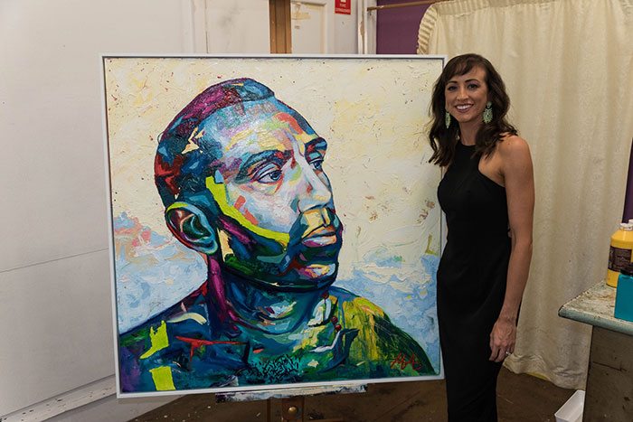 Artist Megan Adams with her portrait of Adam Goodes, titled "Colour Doesn't Matter"