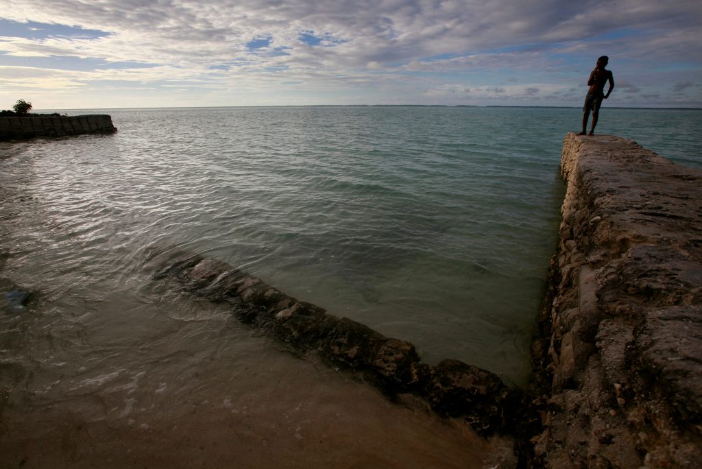A boy stands on top of a seawall near the village of Tangintebu on South Tarawa in the central Pacific island nation of Kiribati May 26, 2013. REUTERS/David Gray