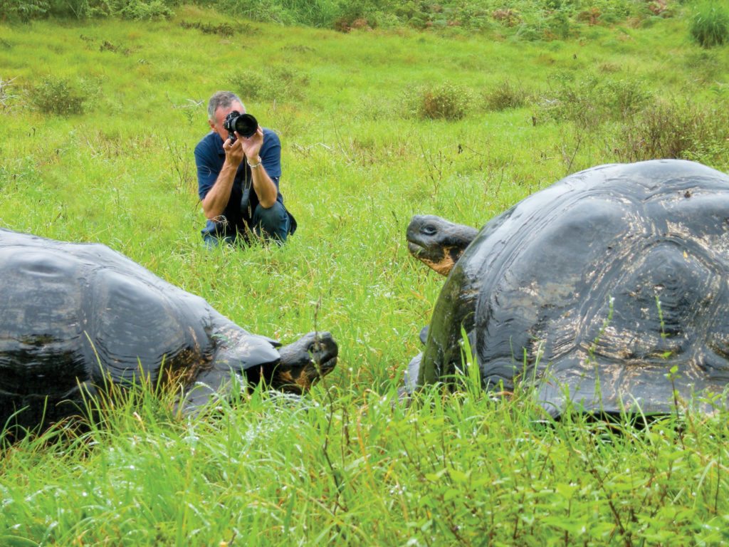 Photographer (Sven Lindblad) in Galapagos with giant tortoises.