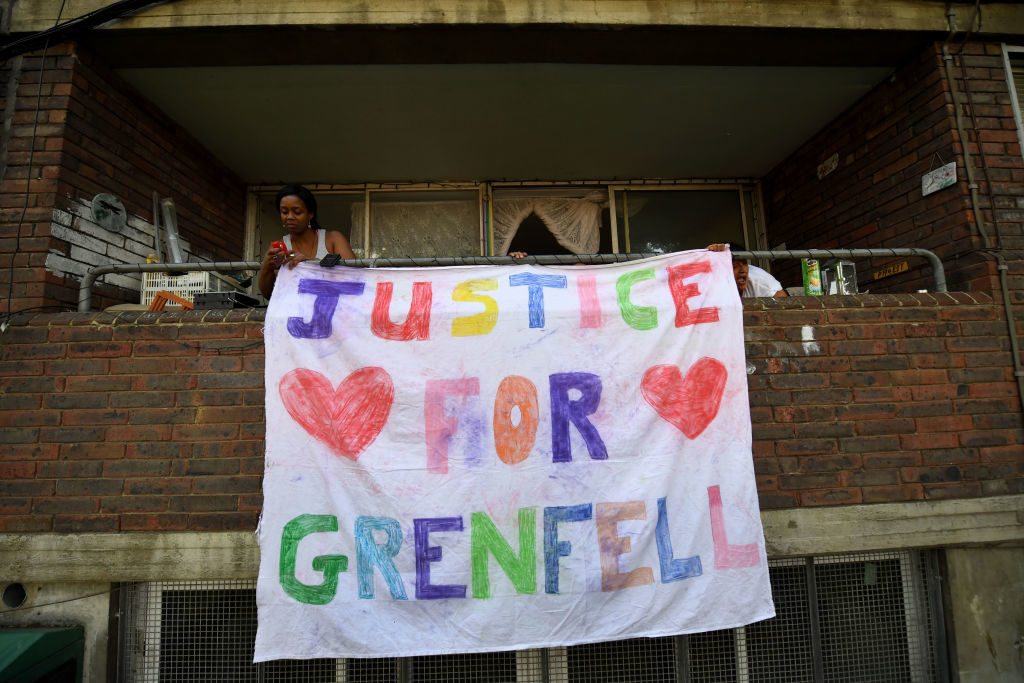 Residents hang a banner demanding Justice for Grenfell, at a block of flats opposite the Grenfell Tower, 

Photo: CHRIS J RATCLIFFE/AFP/Getty Images)