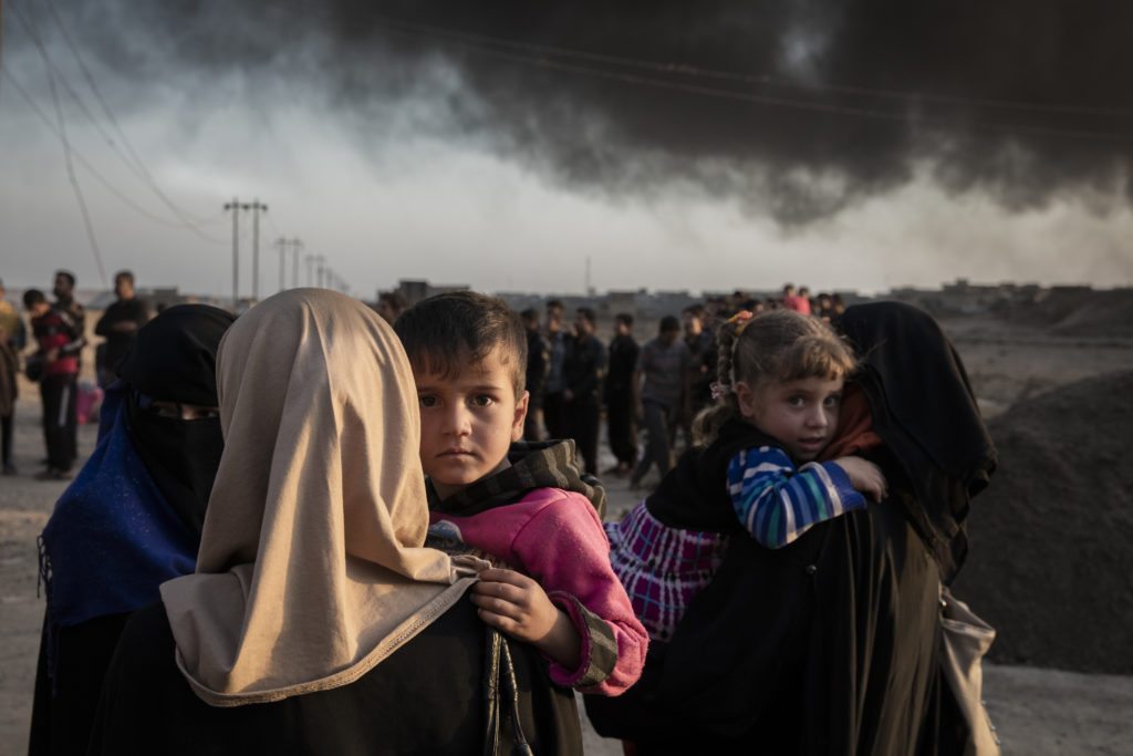 Families displaced by fighting in the village of Shora, 25 kilometres south of Mosul, gather at an army checkpoint on the outskirts of Qayyarah. Around 3.3 million Iraqis, ten per cent of the population of Iraq, have fled their homes since fighting in several parts of the country intensified in March 2014. 