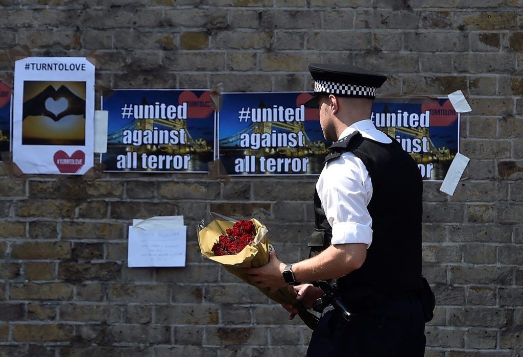 A police officer carries flowers to leave alongside of messages near to where a van was driven at muslims in Finsbury Park, North London, Britain, June 19, 2017. REUTERS/Hannah McKay 