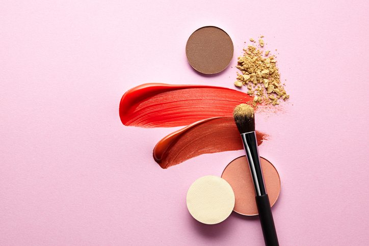 eyeshadow, lipstick, powder and brush on pink background