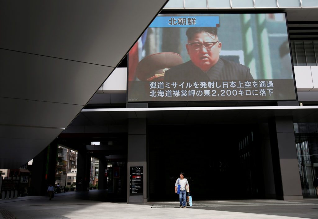 A passerby walks under a TV screen reporting news about North Korea's missile launch in Tokyo, Japan September 15, 2017.  