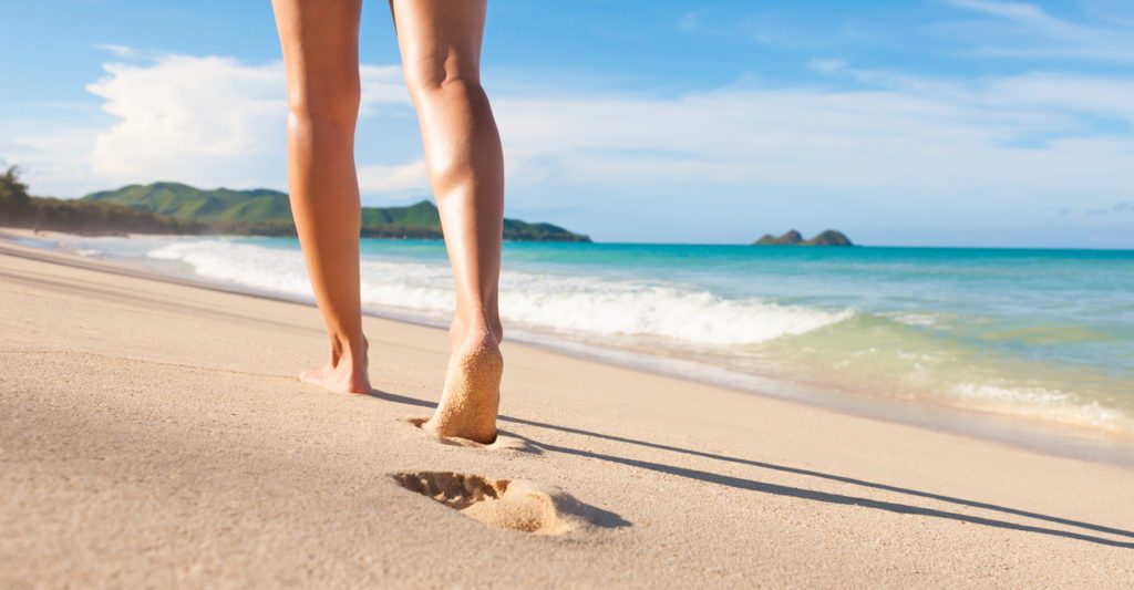 Woman walking on the beach in Hawaii. Summer travel concept.