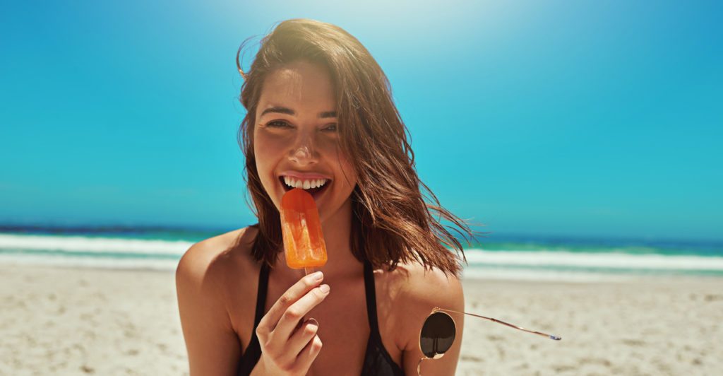Portrait of a sexy young woman enjoying an ice lolly at the beach