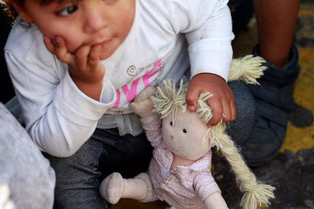 A member of a migrant family from Mexico, fleeing from violence, holds her doll while waiting to enter the United States. REUTERS/Jose Luis Gonzalez