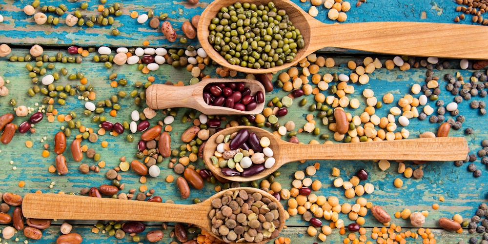 Various legumes on old rustic wooden table, close-up.