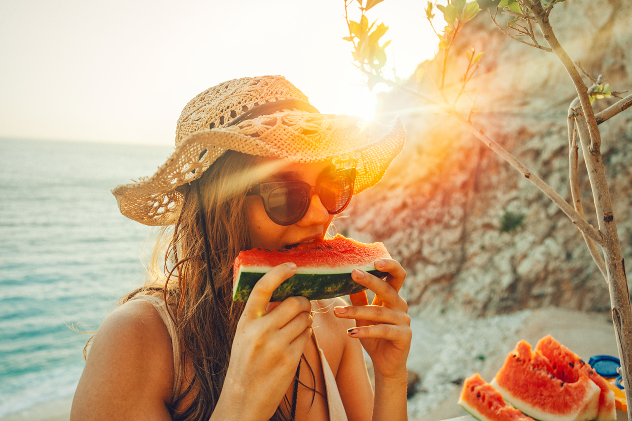 young woman having fun and eating juicy fresh watermelon outdoor at sunset time with snuffler in summer time