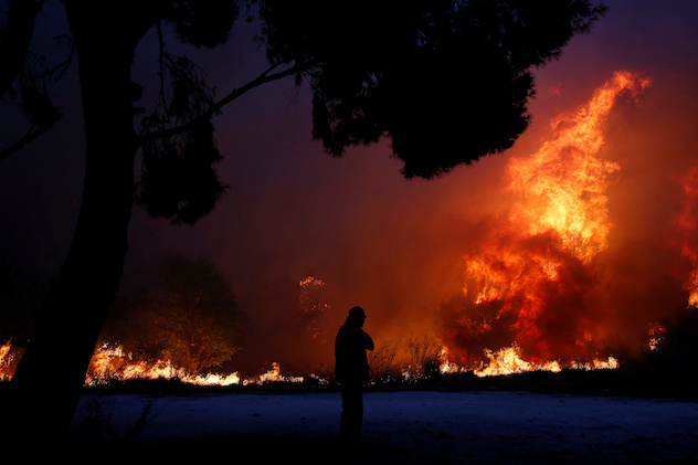 A man looks at the flames as a wildfire burns in the town of Rafina, near Athens, Greece, July 23, 2018. REUTERS/Costas Baltas 