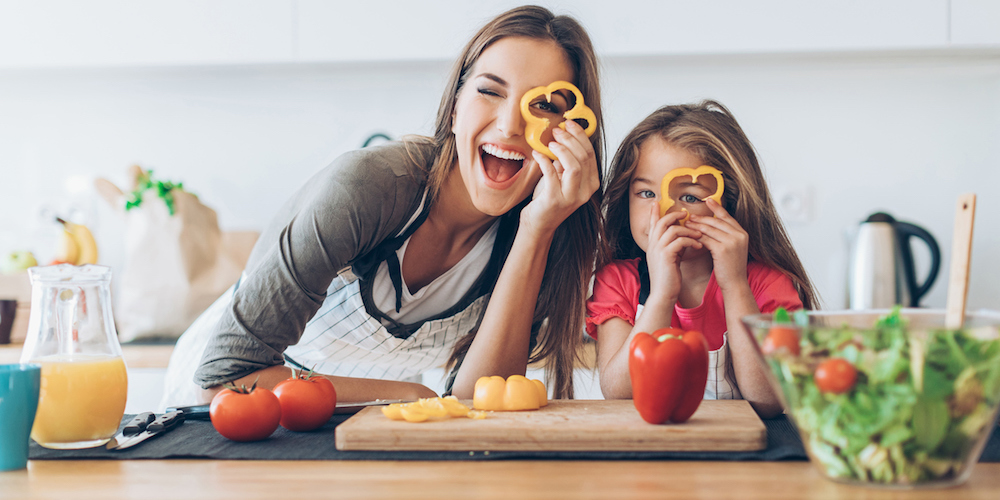 Mother and daughter having fun with the vegetables in the kitchen.