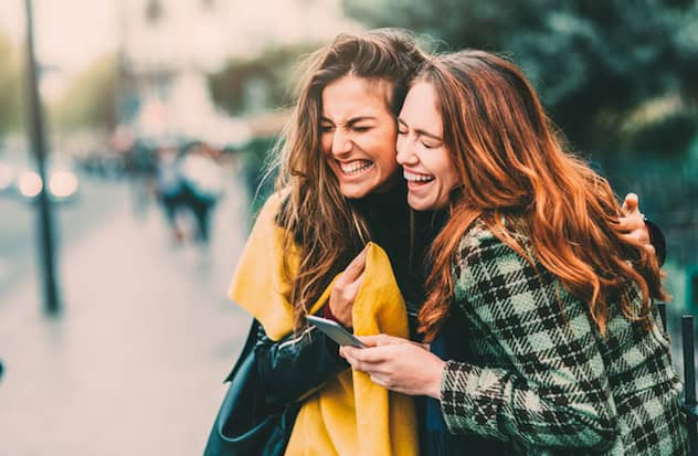 Two friends texting in Paris, France.