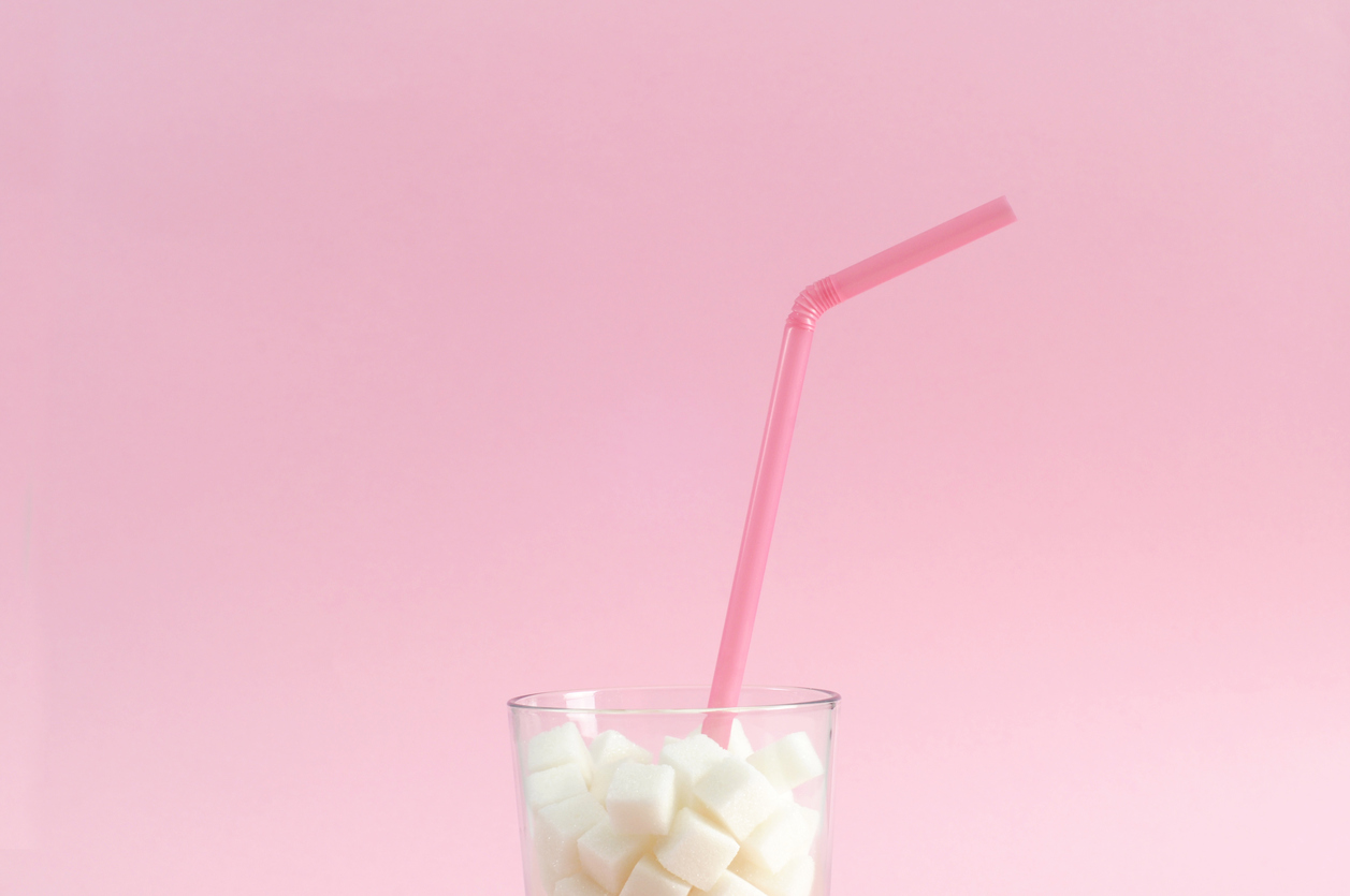 Drinking straw and sugar cubes in glass.