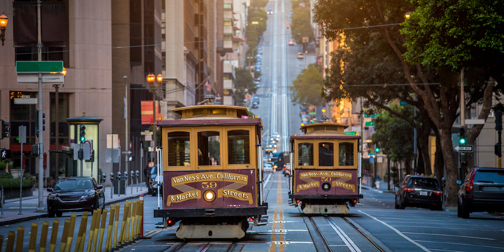 Classic view of historic traditional Cable Cars riding on famous California Street in beautiful early morning light at sunrise in summer, San Francisco, California, USA