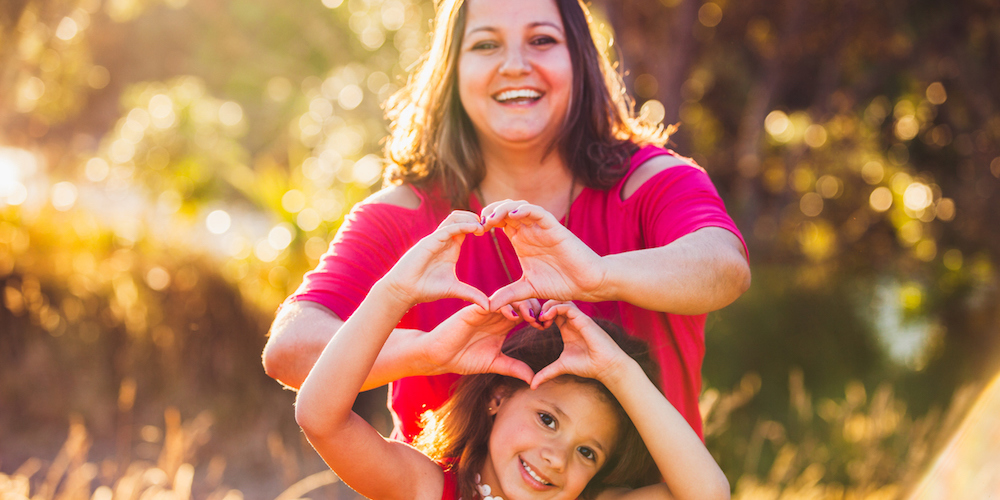 Mother and daughter showing love by making heart shape with hands at Long bay park, Auckland, New Zealand.