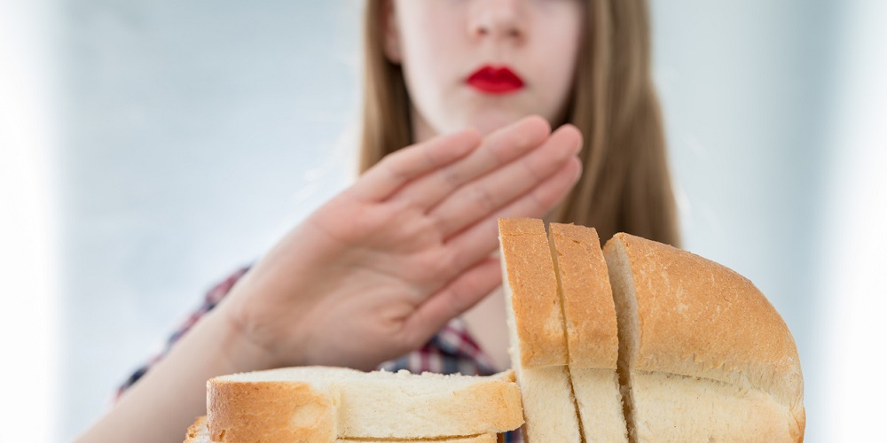 Gluten intolerance concept. Young girl refuses to eat white bread - shallow depth of field - selective focus on bread