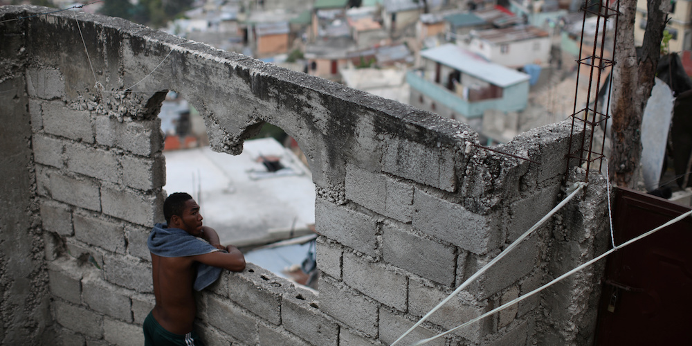 A man leans on the space for a window in an unfinished construction in a slum of Port-au-Prince, Haiti, February 6, 2018. REUTERS/Andres Martinez Casares - RC1340C86E40