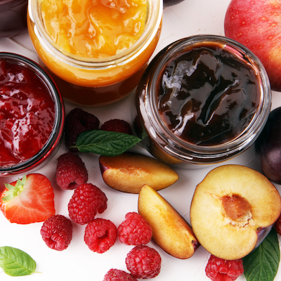 assortment of jams, seasonal berries, plums, mint and fruits.