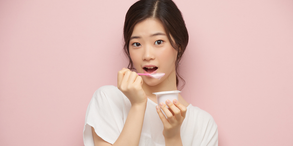 Korean young woman eating tasty yogurt