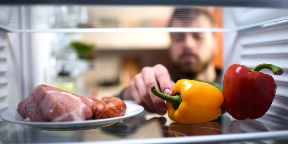 Man picking up bell pepper from the refrigerator.