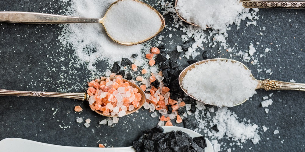 Different Kinds of Salt in Spoons, such as Himalayan Pink, Sea Original, Iodised Table, Sea Salt Flakes, Pink Diamonds, Black Sea Flakes, on Dark Background