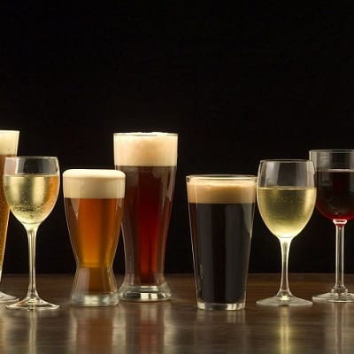 "An assortment of glasses of wine and beer including a classic pilsner flute, a sparkling wine glass, an American half pint glass, a weizen or wheat beer glass, an American pint glass, a white wine glass, and a red wine glass."