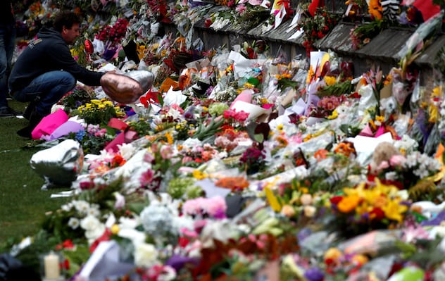 A man places flowers at a memorial site for victims of the mosque shootings at the Botanic Gardens in Christchurch, New Zealand, March 18, 2019. REUTERS/Edgar Su