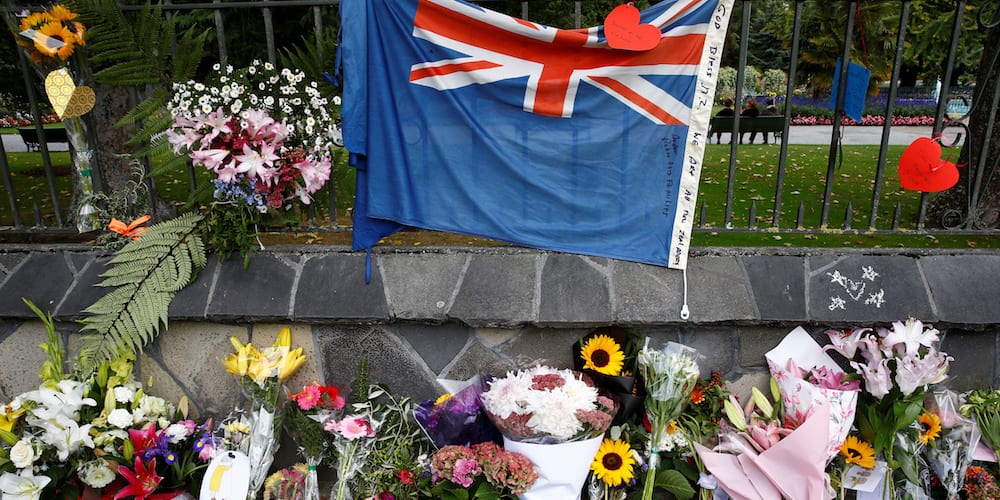 Flowers and a New Zealand national flag are seen at a memorial as tributes to victims of the mosque attacks near Linwood mosque in Christchurch, New Zealand, March 16, 2019. REUTERS/Edgar Su - RC11AFACEFA0