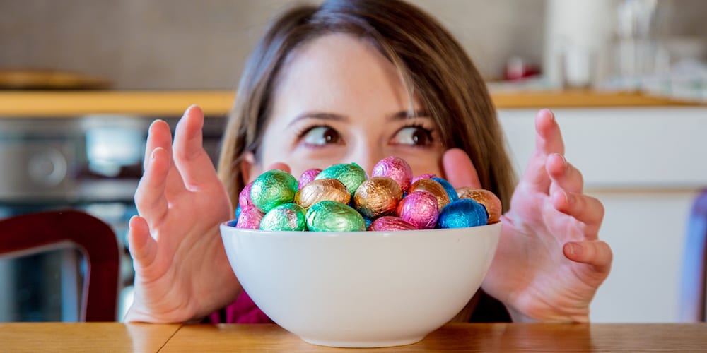 Adult woman and Easter eggs in plate on a wooden table at kitchen in home