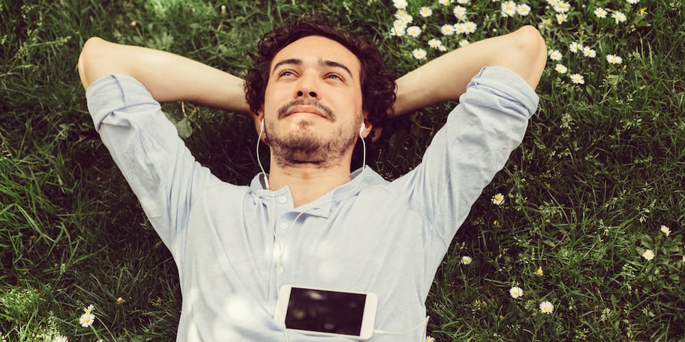 Young man relaxing in the grass and enjoying the music