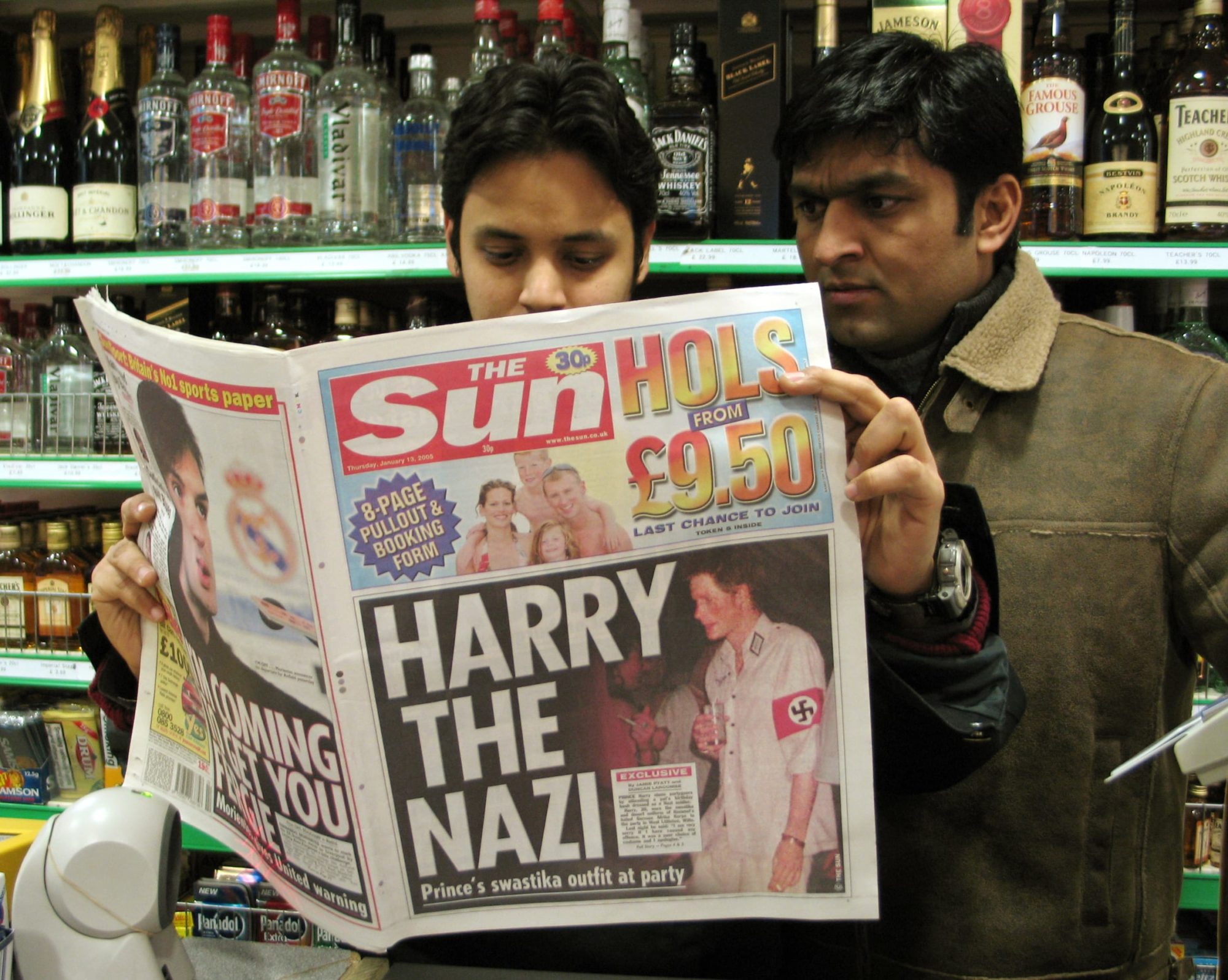 Newsagents Khan and Mohammad Ahmed read a copy of 'The Sun' tabloid in London showing Prince Harry in a Nazi uniform.  Newsagents Khan and Mohammad Ahmed (L) read a copy of 'The Sun' tabloid in London, January 13, 2005, whose front page shows a picture of Britain's Prince Harry wearing a Nazi uniform with a red and black swastika armband during a party at a friend's house on Saturday. Britain's Prince Harry apologised on Thursday after he wore the Nazi uniform to a costume party two weeks before Queen Elizabeth is due to lead the country's holocaust memorial events. REUTERS/David Loh - RP5DRIFXPDAA