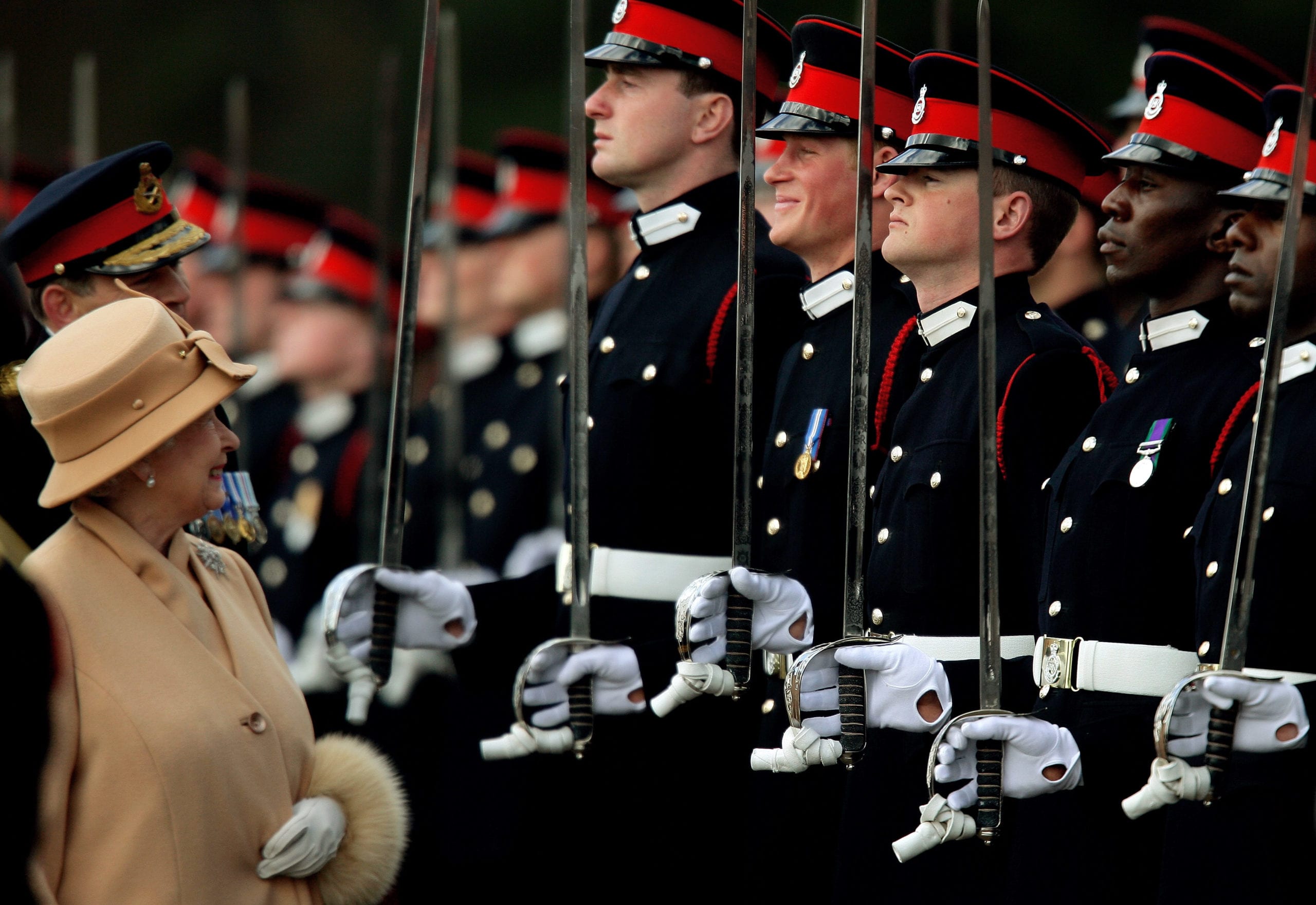 Britain's Queen Elizabeth smiles with Prince Harry during the Sovereign's Parade at the Royal Military Academy in Sandhurst, southern England April 12, 2006. Harry, once dubbed a royal wild child for underage drink and drug antics, graduated as an army officer on Wednesday before joining a regiment that could be sent to Iraq or Afghanistan.   REUTERS/Dylan Martinez - GM1DSJGYFPAA