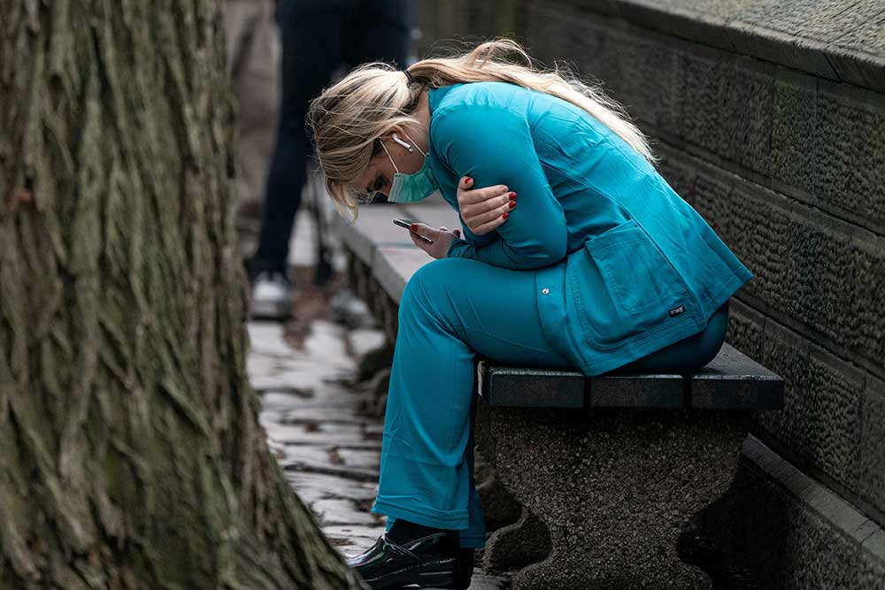 <em>A healthcare worker sits on a bench near Central Park in the Manhattan borough of New York City</em>