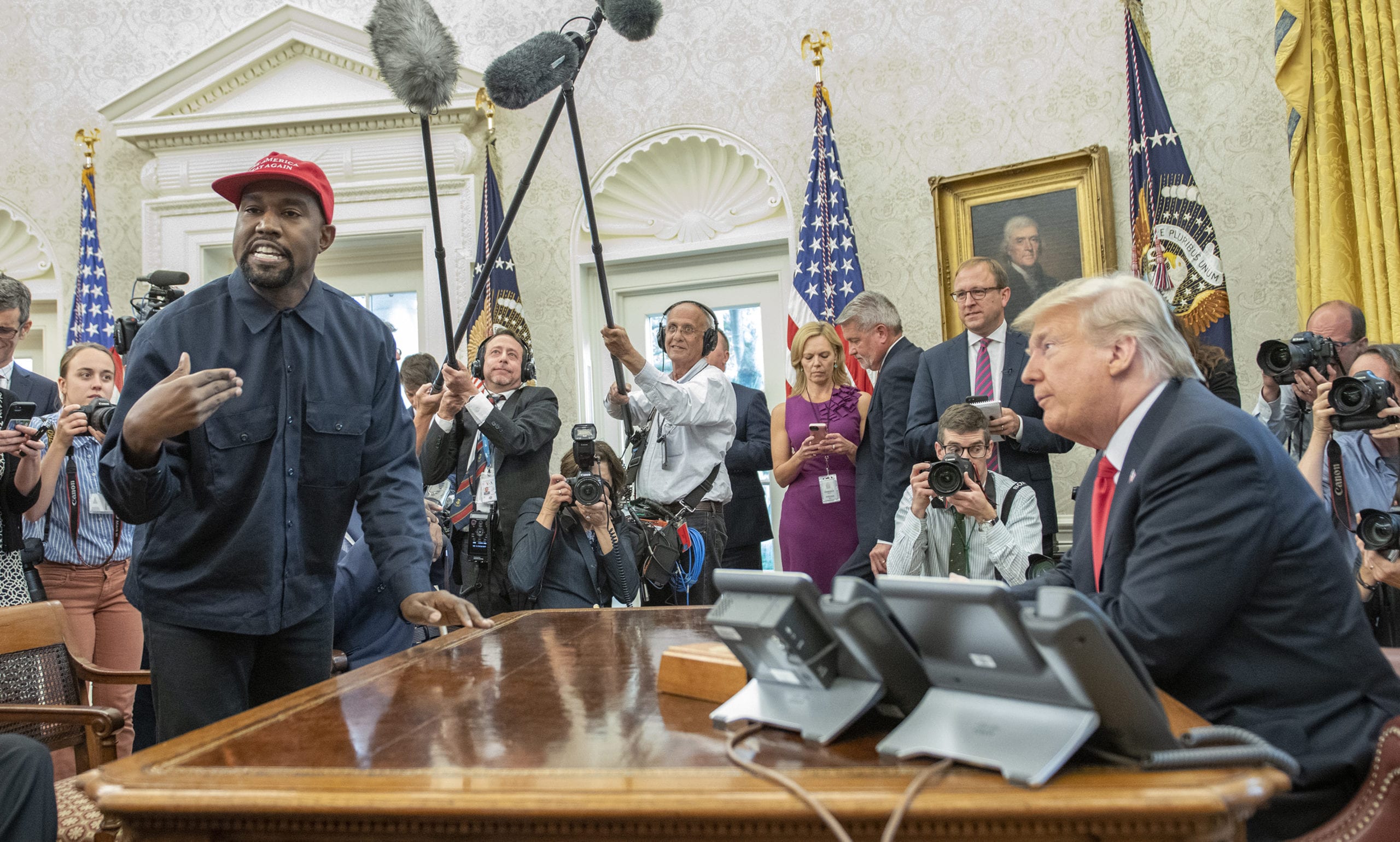 Surrounded by members of the press and others, Kanye West stands as he talks with US President Donald Trump in the White House's Oval Office, Washington DC, October 11, 2018.(Photo by Ron Sachs/Consolidated News Pictures/Getty Images)