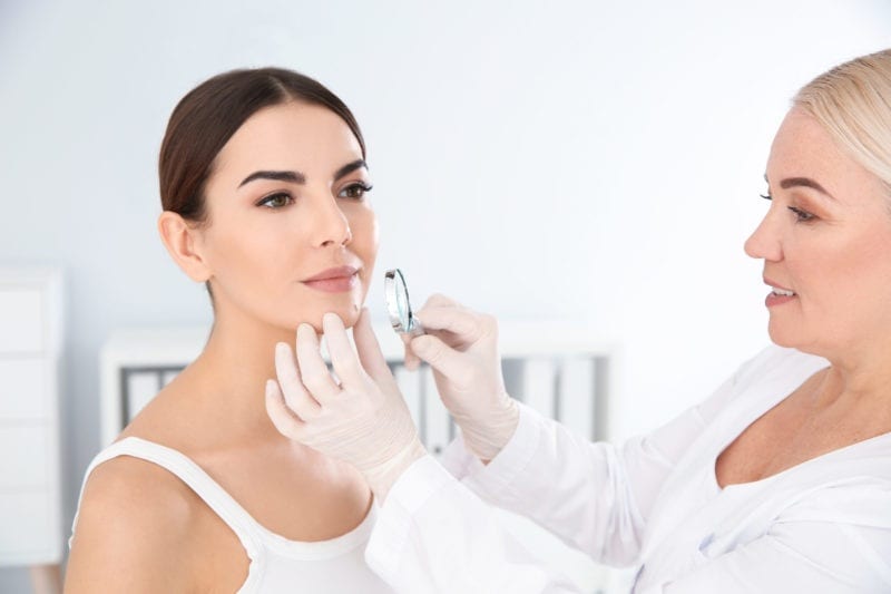 Beauty Professional examining patient’s skin concern in clinic
