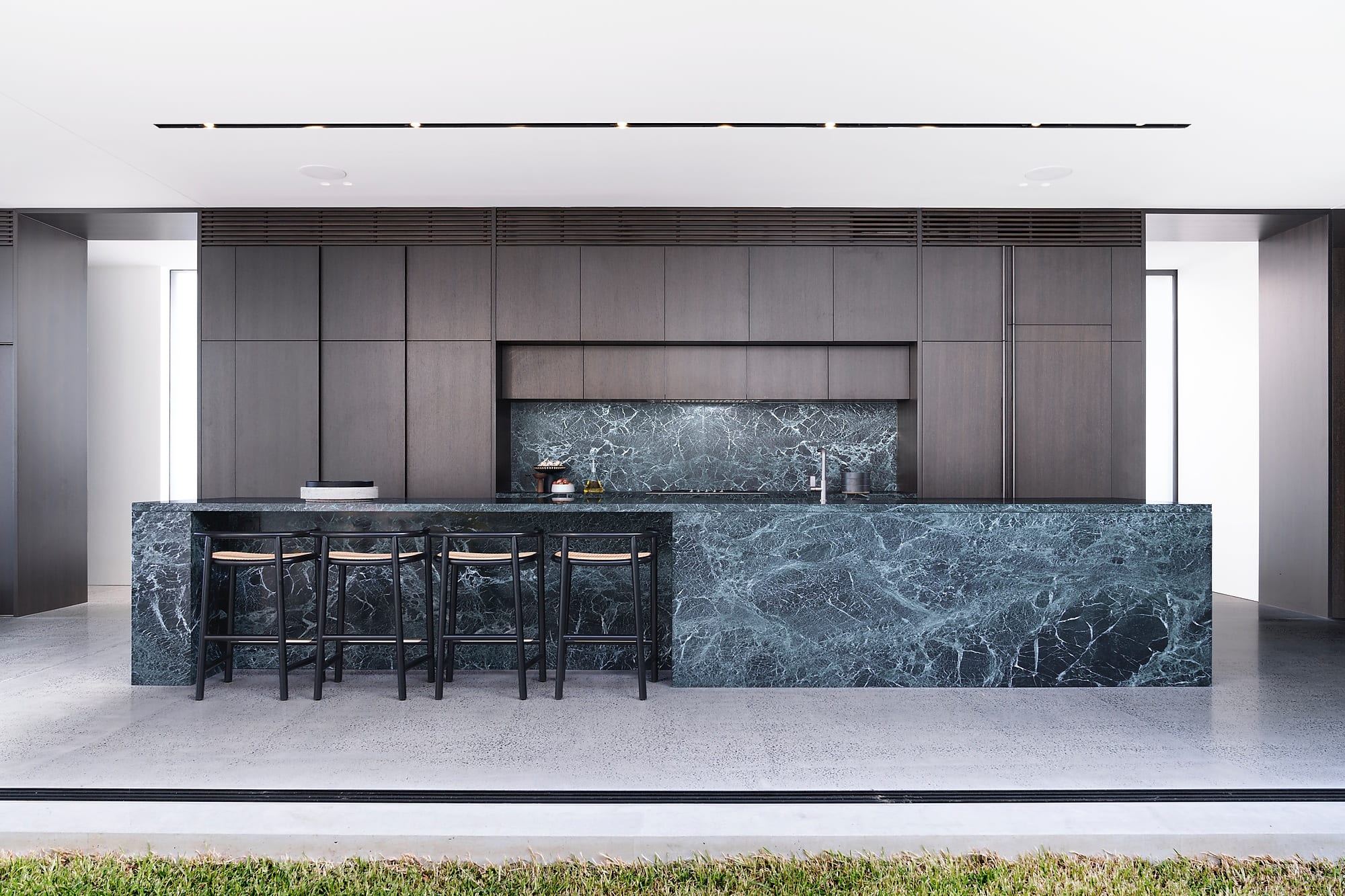 Bronte Terraced House features off-form concrete which provides a feeling of groundedness, timber screens, glazing and charcoal metal surfaces provide textural contrast.