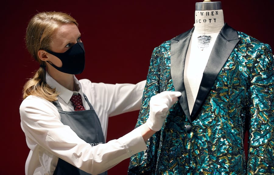 A gallery assistant poses for a photograph next to the Oak Leaf 'Glamouflage' jacket designed for Mick Jagger by designer L'Wren Scott at Christie's in London, Britain, June 10, 2021. REUTERS/John Sibley