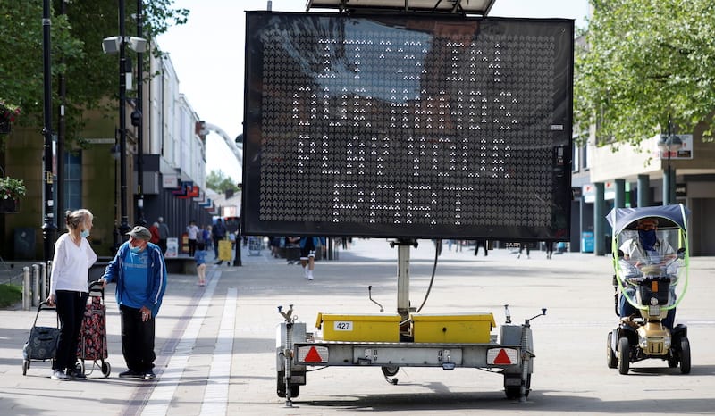 People walk past an information board, amid the outbreak of the coronavirus disease (COVID-19), in Bolton, Britain, June 16, 2021. REUTERS/Phil Noble