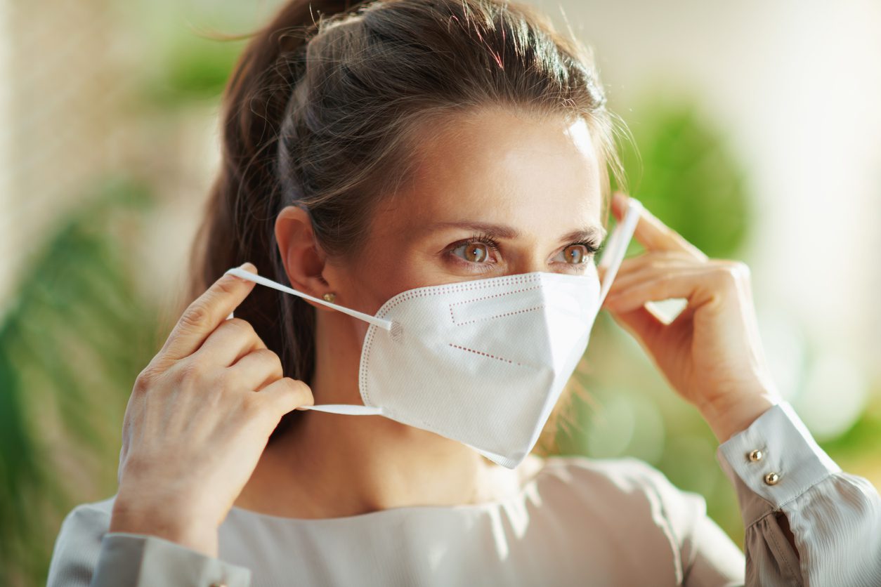 woman putting on N95 mask