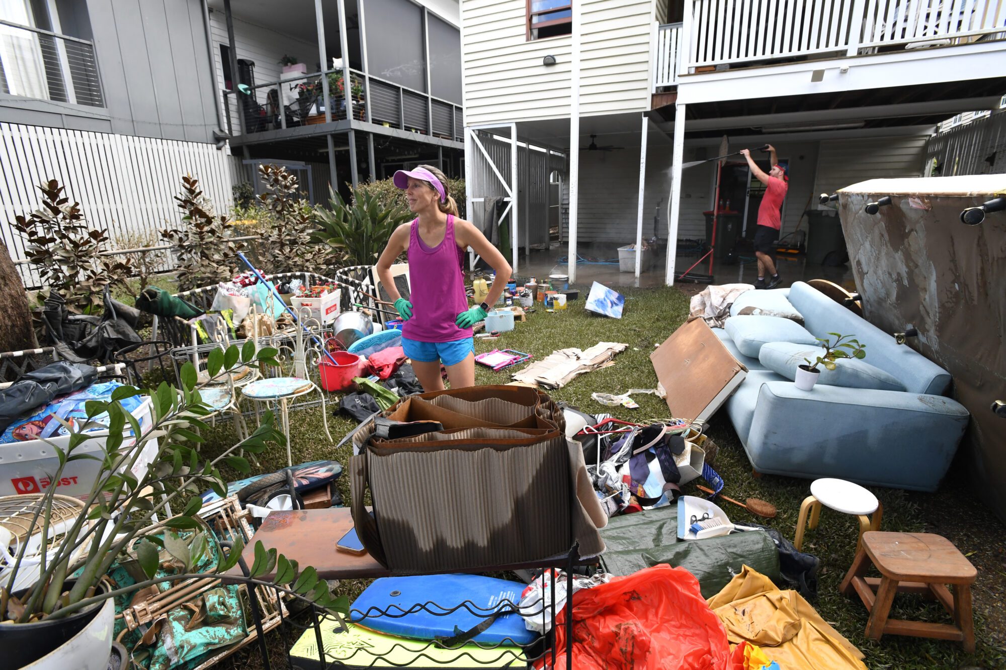 Jane Knox is seen cleaning up her flood damaged property in the suburb of Auchenflower in Brisbane, Wednesday, March 2, 2022. (AAP)