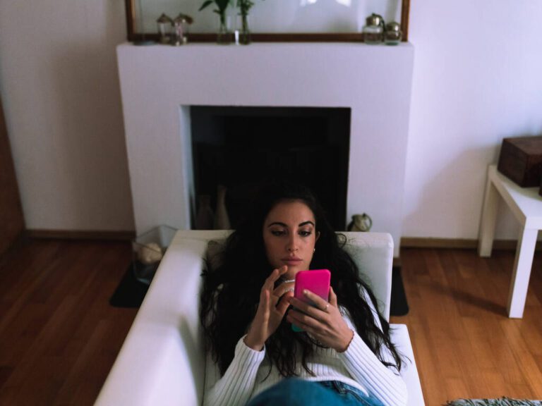 Young woman on sofa, looking at mobile phone