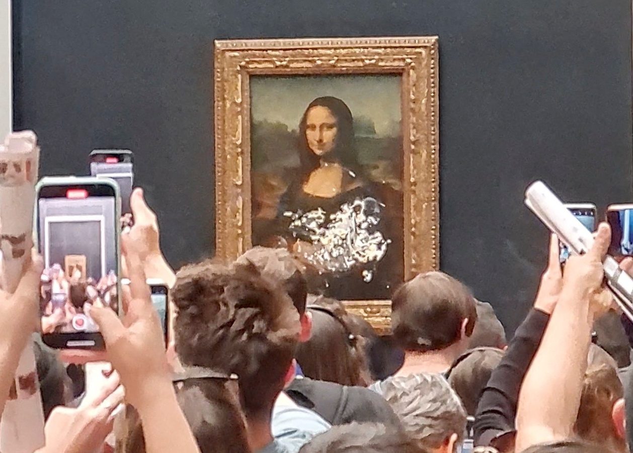 Visitors take pictures and video of the painting "Mona Lisa" after cake was smeared on the protective glass at the Lourve Museum in Paris, France May 29, 2022 in this screen grab obtained from a social media video. Twitter/@klevisl007