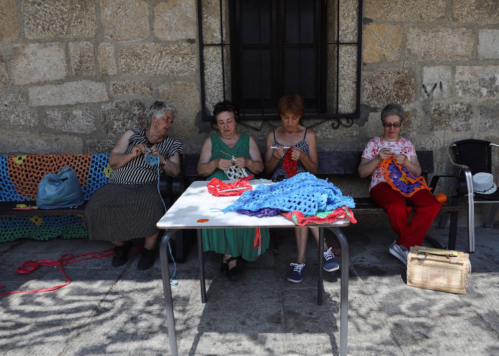 A group of women use recycled materials to weave canopies during a workshop in Valverde de la Vera, as part of the "Weaving the Streets" project, to protect people from the intense summer heat, in the province of Caceres, Spain, August 26, 2022. REUTERS/Isabel Infantes
